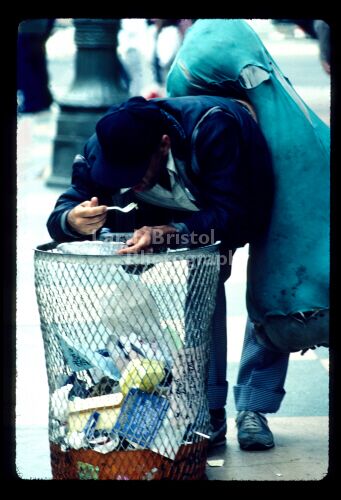 LA Street Person eating peas -Garbage can